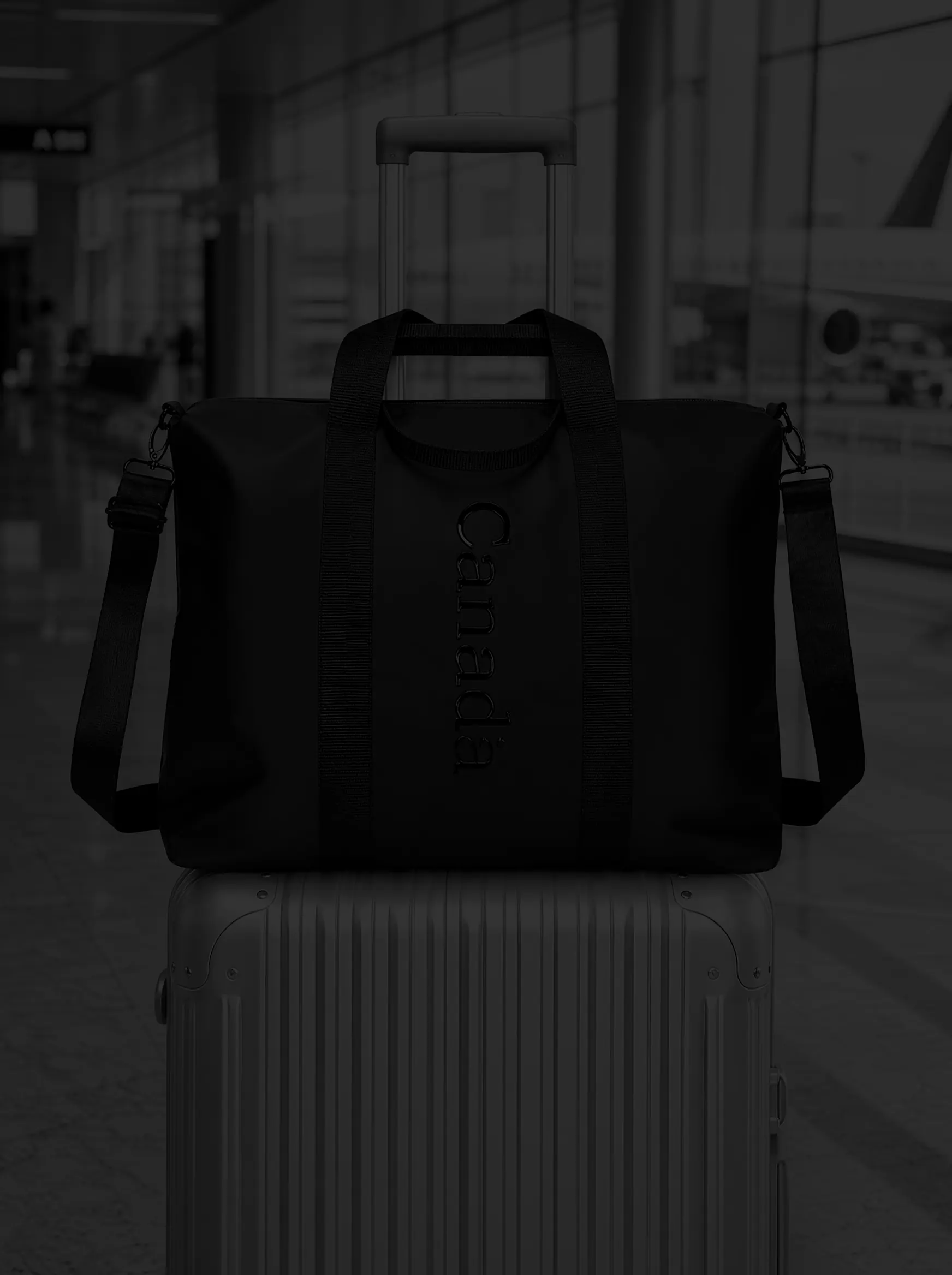 A black Nordin sleeve bag hanging on the handle of a silver suitcase in an airport terminal