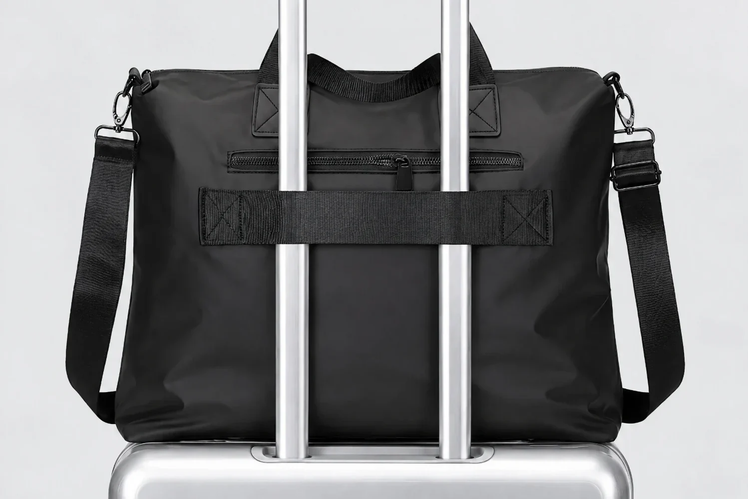Back of the bag with its sleeve strap slid over the two rails of a suitcase handle